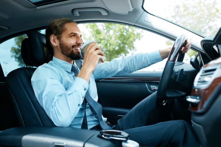 young business man driving while drinking coffee